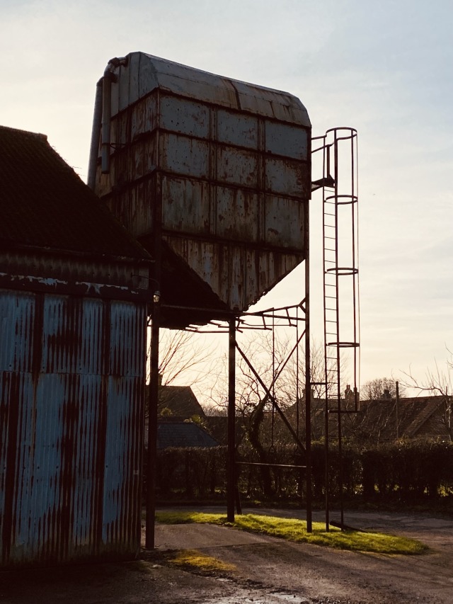 A farm silo backlit by the setting sun